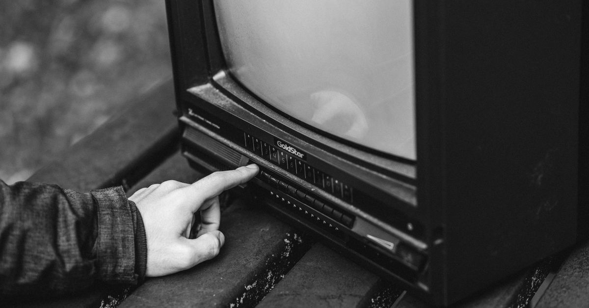 Homme ajustant une télévision ancienne posée sur une table en bois à l'extérieur dans la nature
