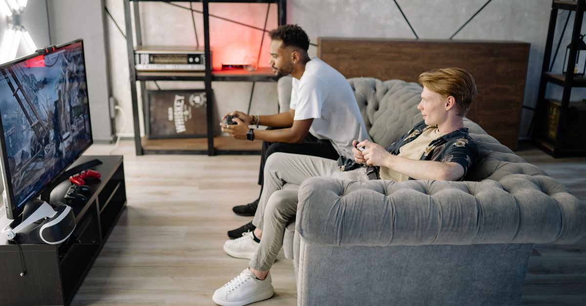Deux hommes détendus jouent à des jeux vidéo sur une console devant une télévision dans un salon
