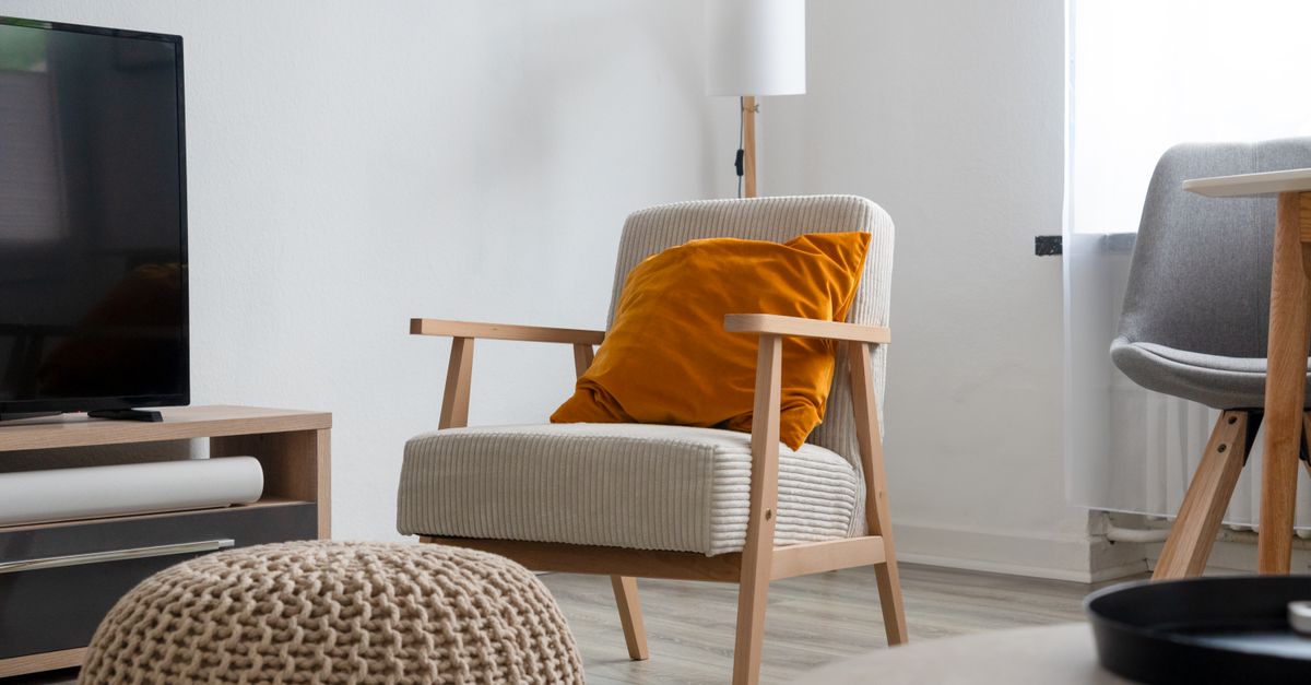 Salon moderne avec fauteuil confortable, coussin doux et mobilier épuré près d'une télévision à écran plat