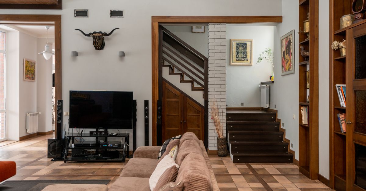 Salon moderne avec canapé confortable et télévision près d’un mur décoré et étagères en bois
