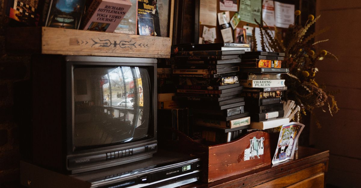 Espace salon vintage avec ancienne télévision, cassettes VHS empilées et objets décoratifs nostalgiques