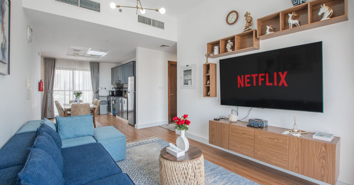 Salon moderne avec canapé bleu et télévision affichant un service de streaming