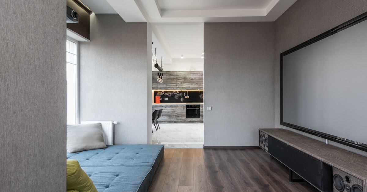 Grand téléviseur contemporain face à un matelas bleu et des coussins dans un salon design