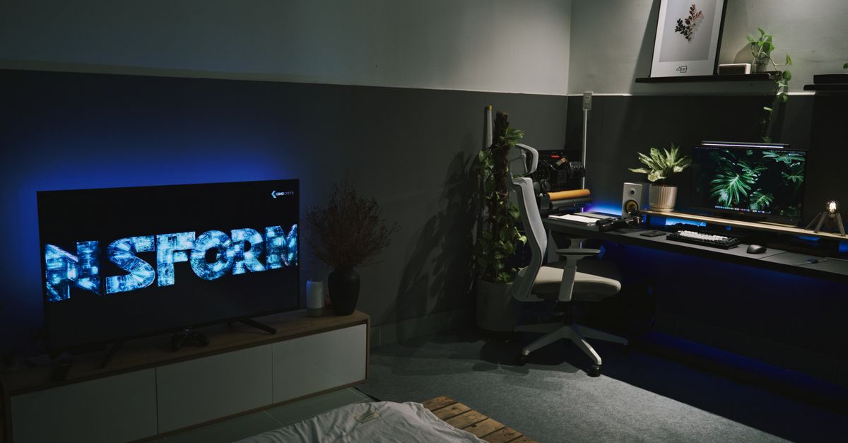 Salle de jeux moderne avec éclairage bleu et plusieurs écrans allumés sur un bureau sombre