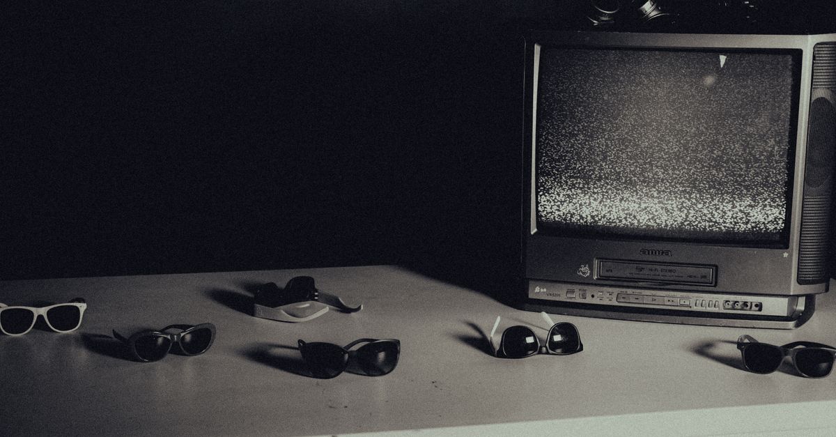 Ancienne télévision affichant de la neige posée sur une table blanche avec plusieurs lunettes de soleil autour