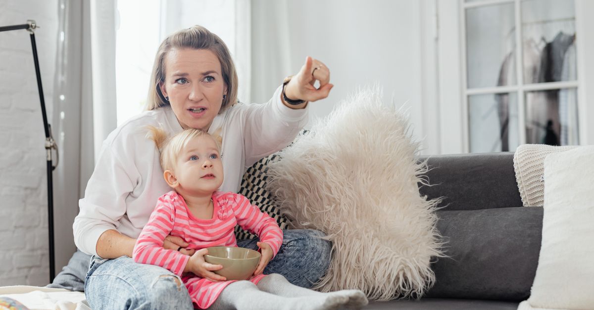 Mère et fille assises sur le canapé, partageant un moment devant un écran de télévision