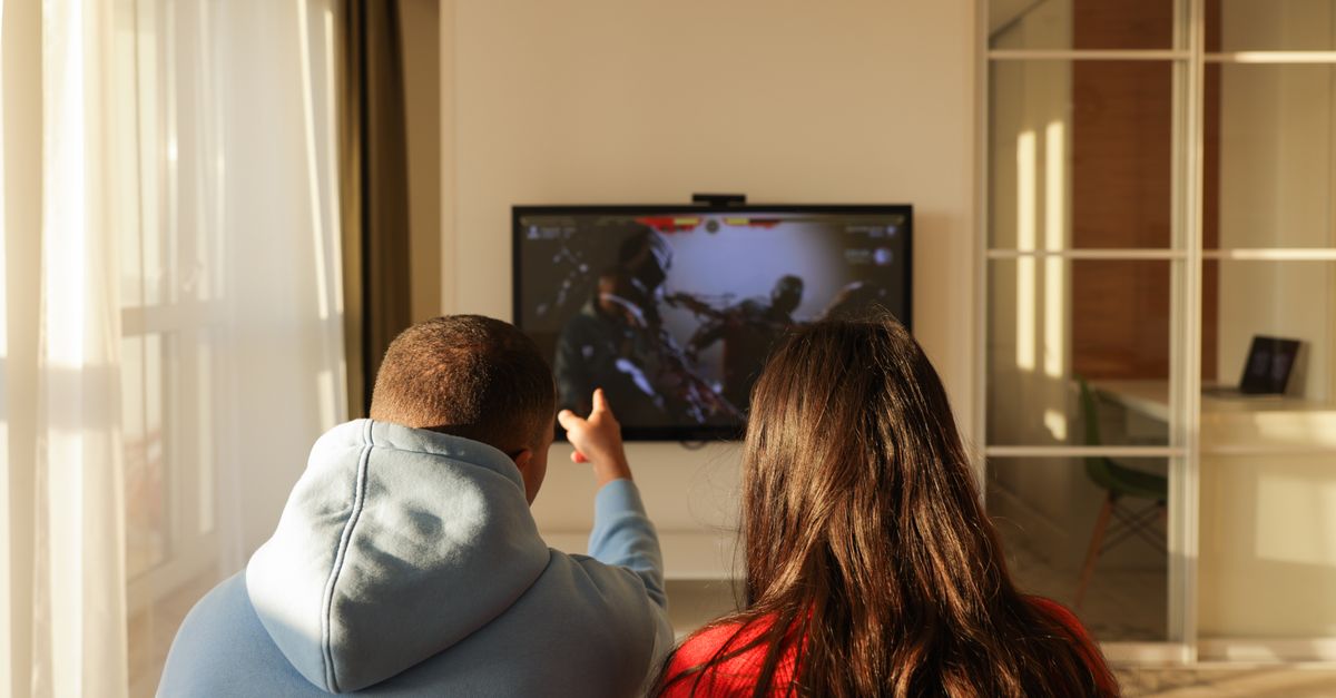 Couple souriant jouant à des jeux vidéo dans un salon chaleureux, ambiance détendue et conviviale