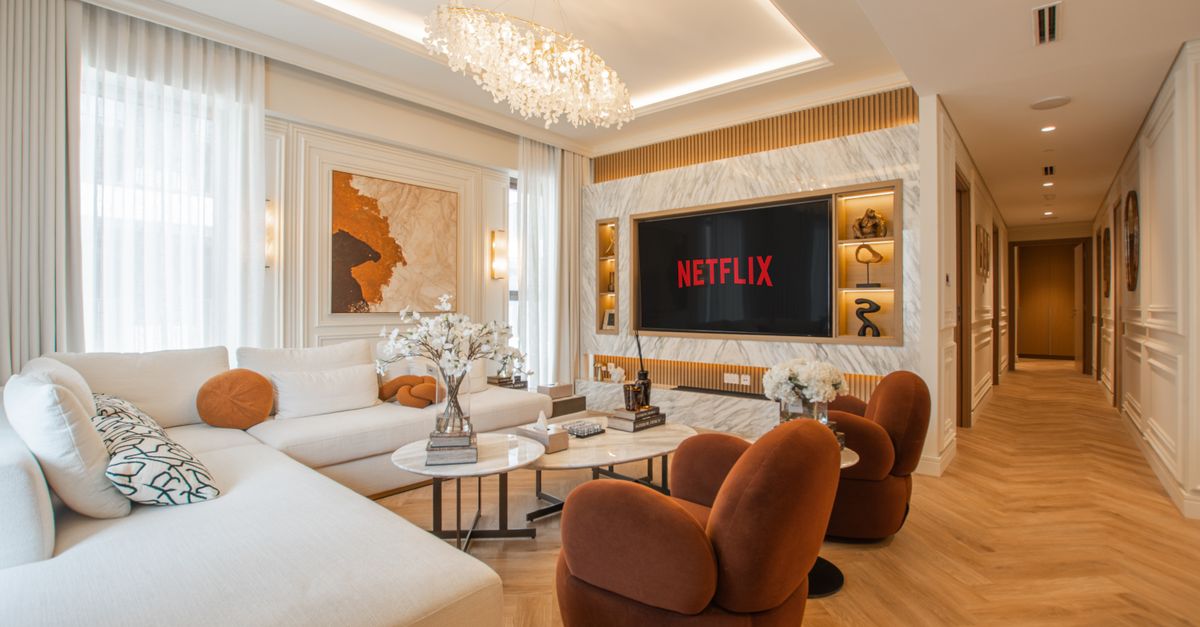 Grand salon moderne avec télévision allumée, canapé confortable et décoration élégante.