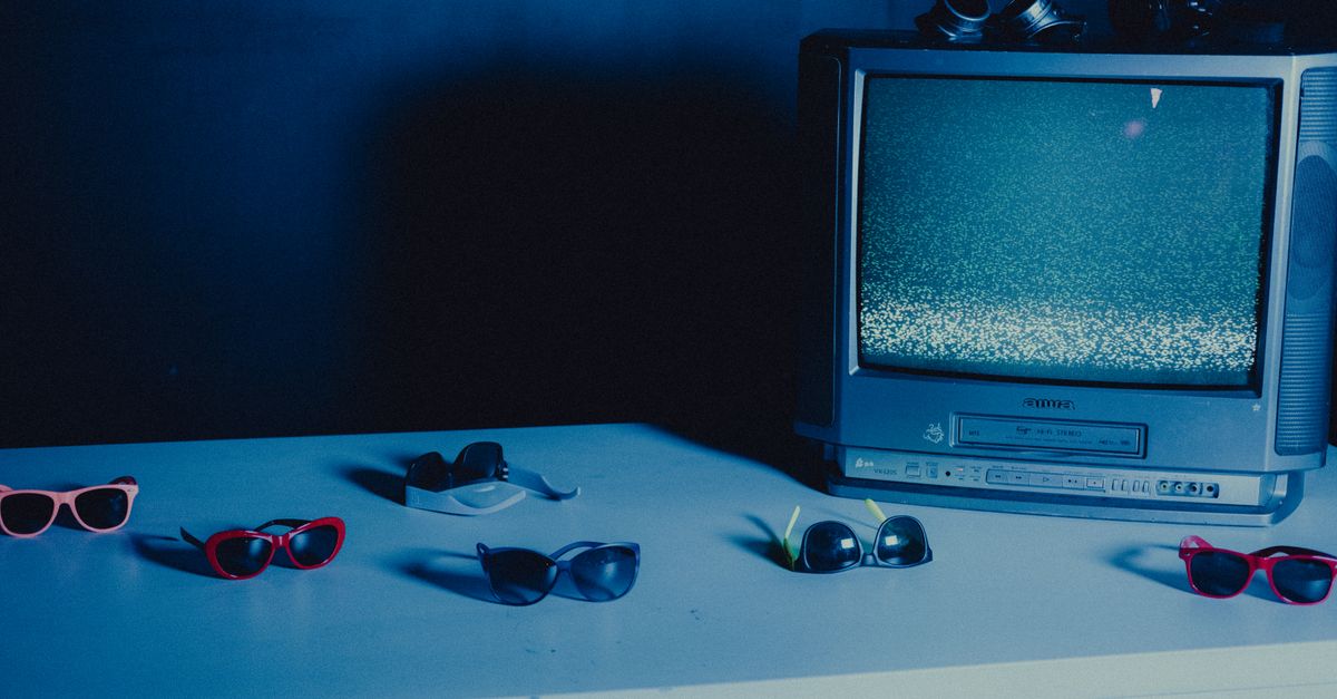 Vieille télévision avec parasites, entourée de lunettes de soleil colorées sur table bleue