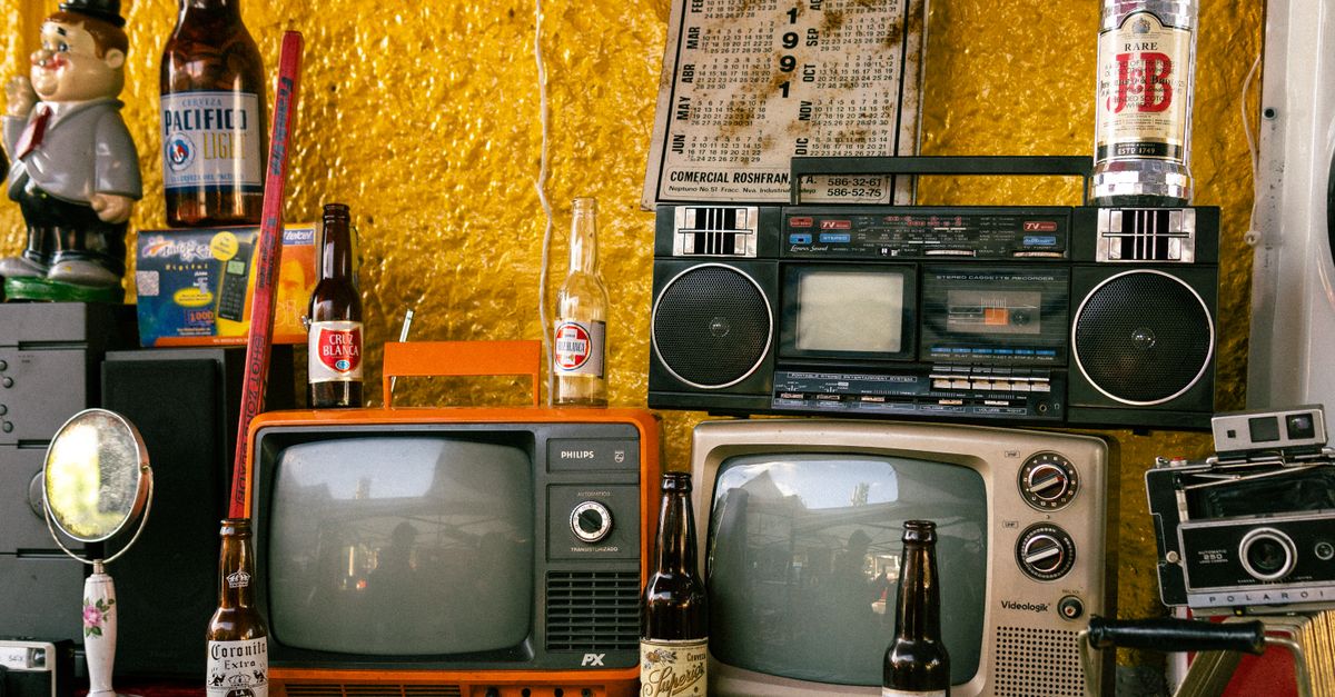 Vieux téléviseur, lecteur VHS et bouteilles disposés sur une table dans une ambiance rétro