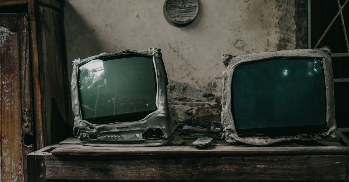Deux téléviseurs anciens brûlés posés dans une pièce délabrée et poussiéreuse