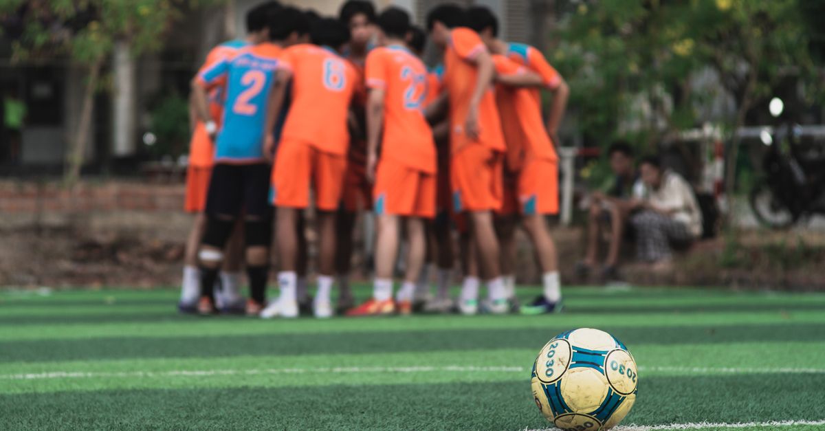 Ballon de football sur le terrain avec des adolescents discutant en arrière-plan
