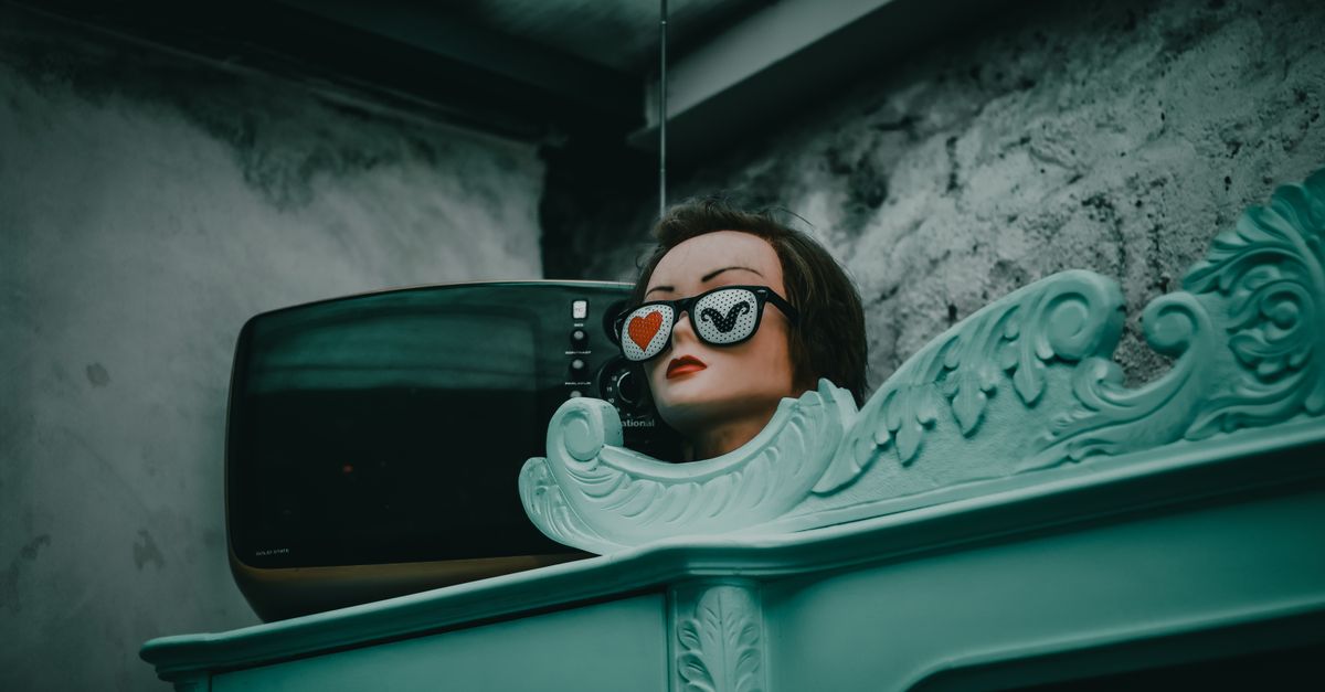 Mannequin avec lunettes en forme de cœur près d’une télévision rétro dans un décor vintage