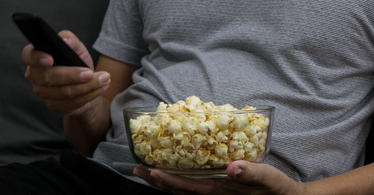 Personne avec bol de pop-corn et télécommande profitant d’une soirée film confortable