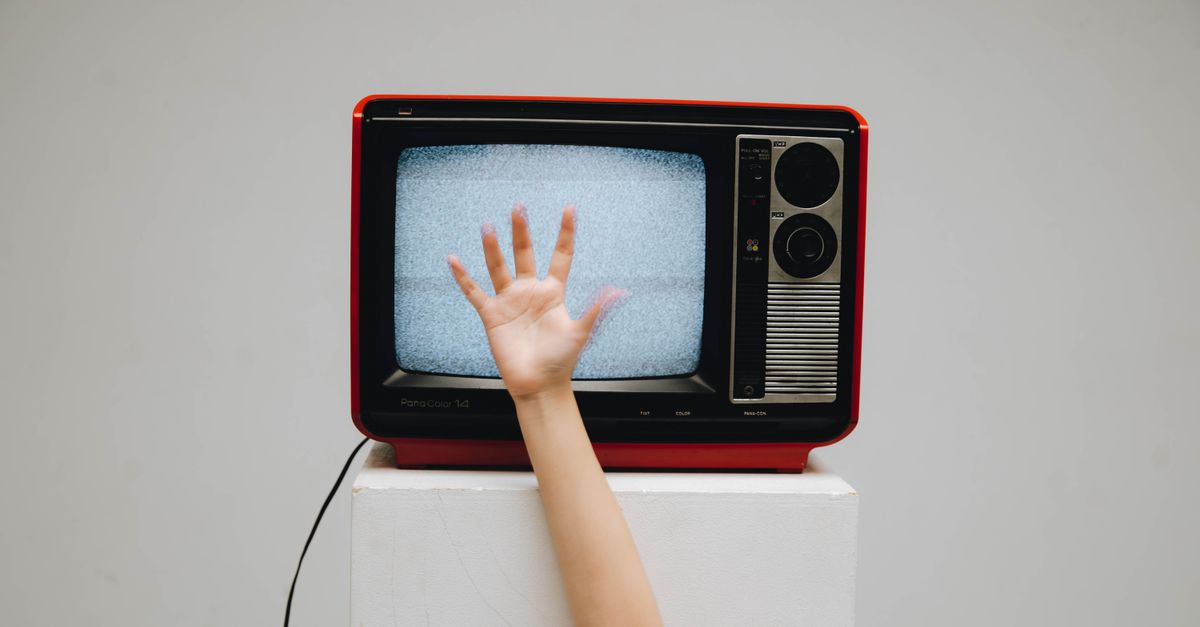Main tendue vers un écran de télévision rétro affichant de la neige visuelle