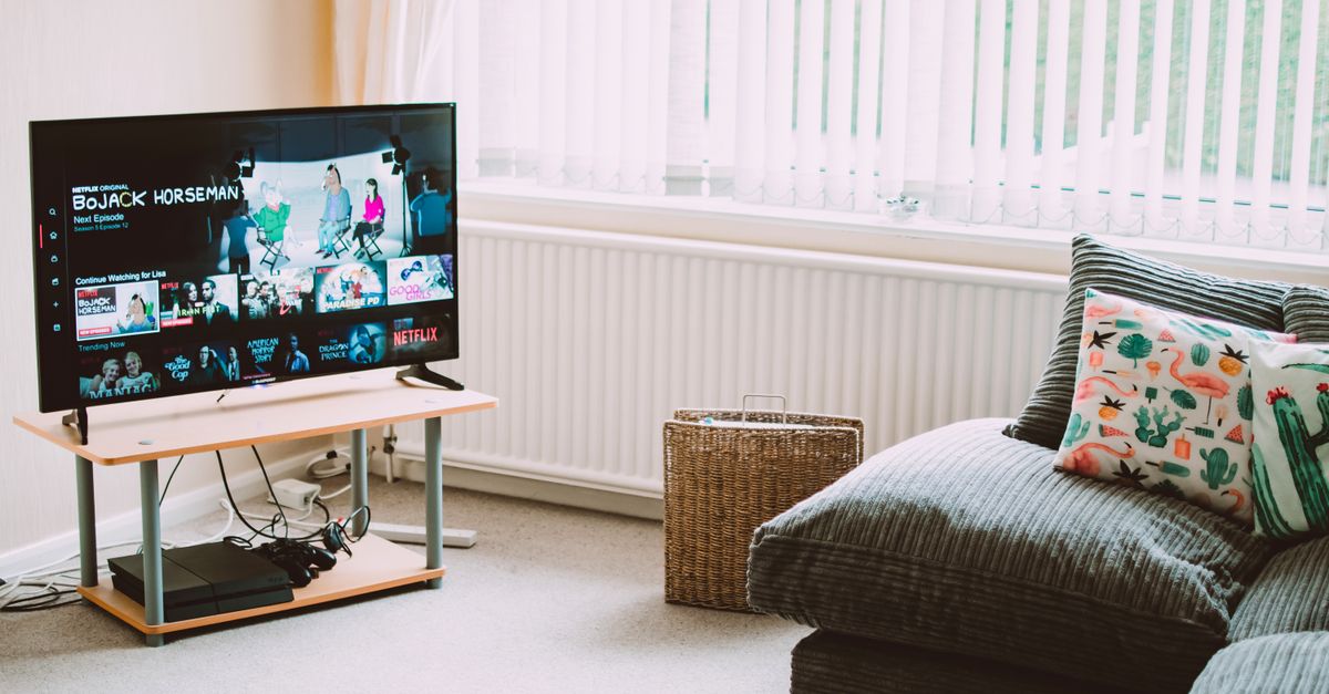 Salon moderne avec canapé, coussins décoratifs et télévision diffusant une émission populaire