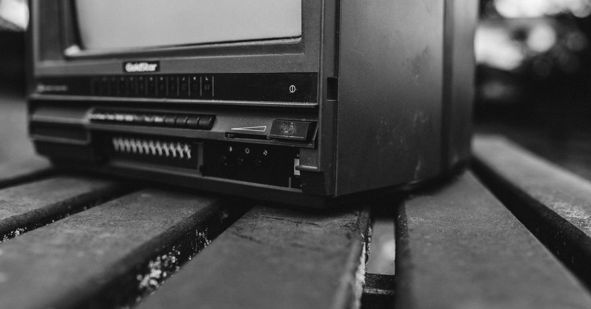 Petit téléviseur ancien posé sur des planches en bois dans une rue urbaine floue