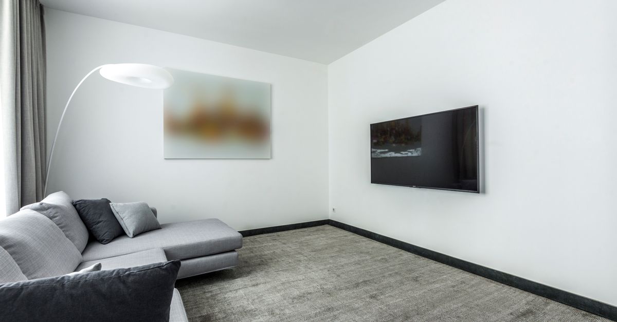 Salon moderne avec canapé gris et télévision posée sur un meuble minimaliste