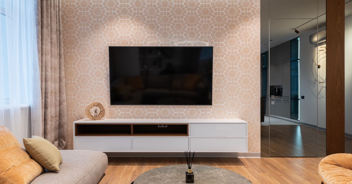 Salon moderne avec canapé, coussins et télévision murale sous un meuble dans une pièce claire
