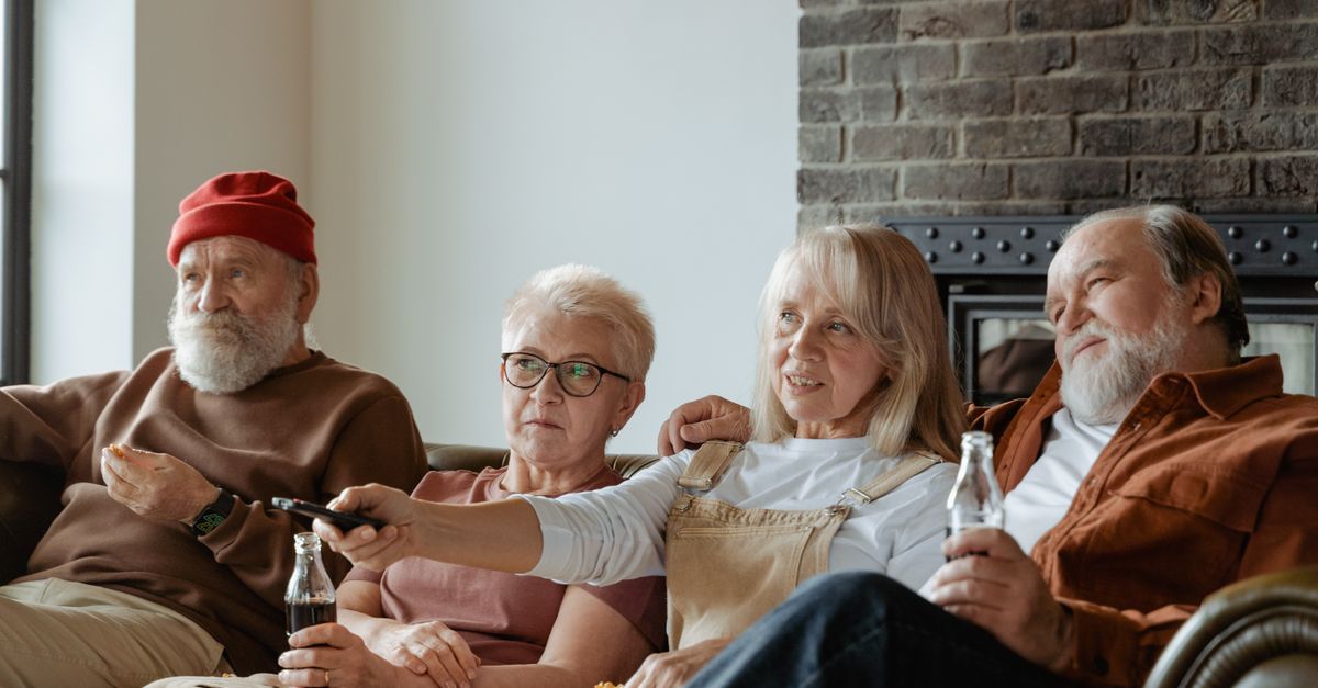 Groupe de personnes âgées assises et regardant la télévision dans un salon confortable