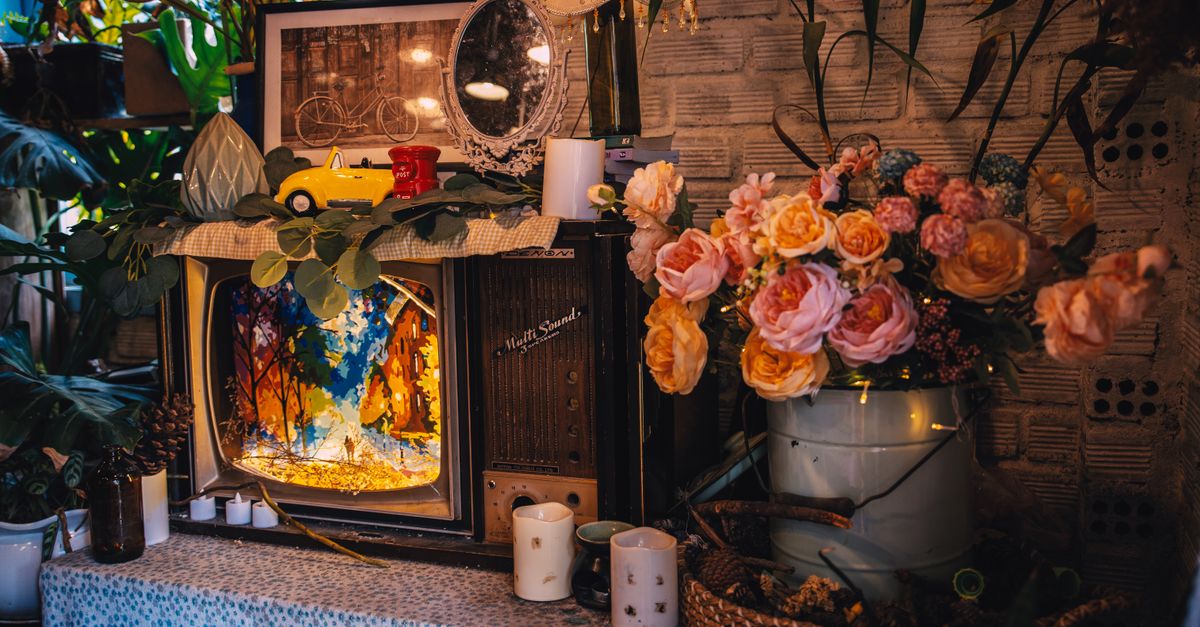Décor vintage chaleureux avec fleurs, vieux téléviseur et détails artistiques dans une pièce cosy