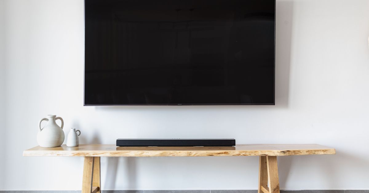 Salon moderne avec télévision murale et meuble en bois minimaliste sous l'écran.
