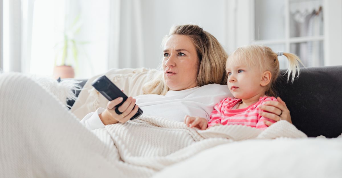 Mère et fille assises sur un canapé, regardant la télévision dans le salon.
