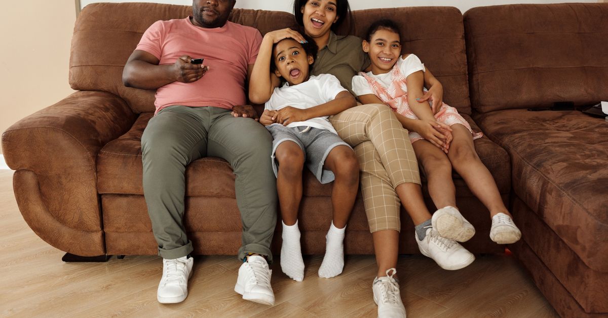 Famille souriante réunie sur un canapé profitant d’un moment convivial devant la télévision