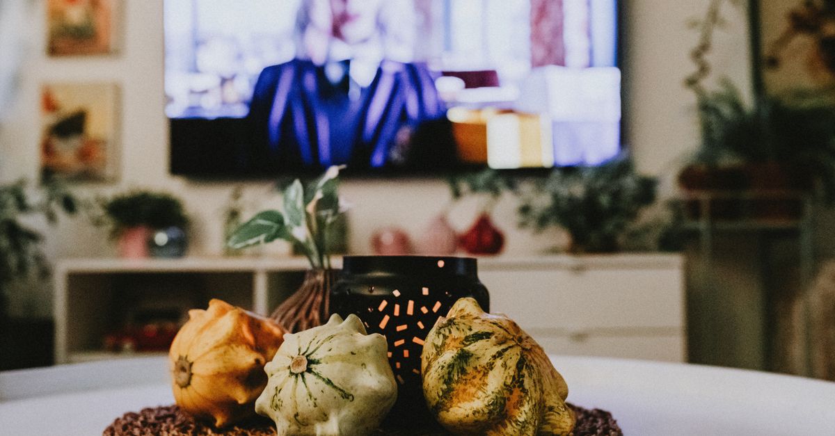 Table décorée aux couleurs d’automne avec courges et bougie dans une ambiance chaleureuse